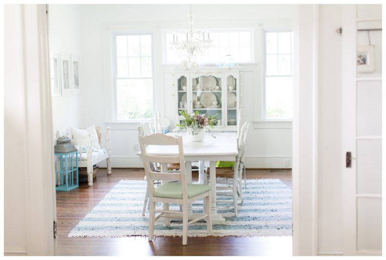 A small table in the dining room with a blue and white rug underneath it.