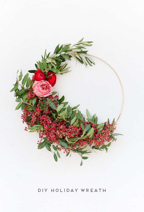A floral wreath with greenery and red and pink flowers.