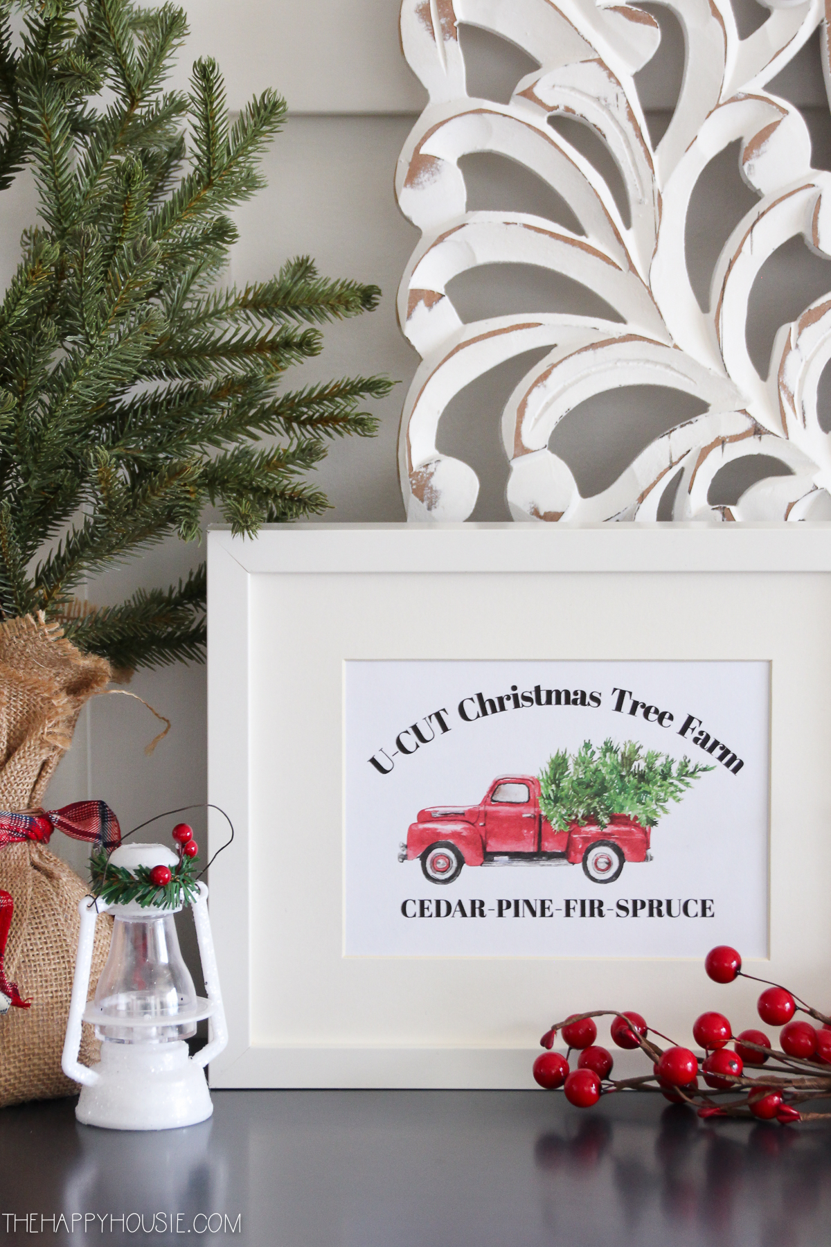 A framed picture of a red truck carrying a Christmas tree
