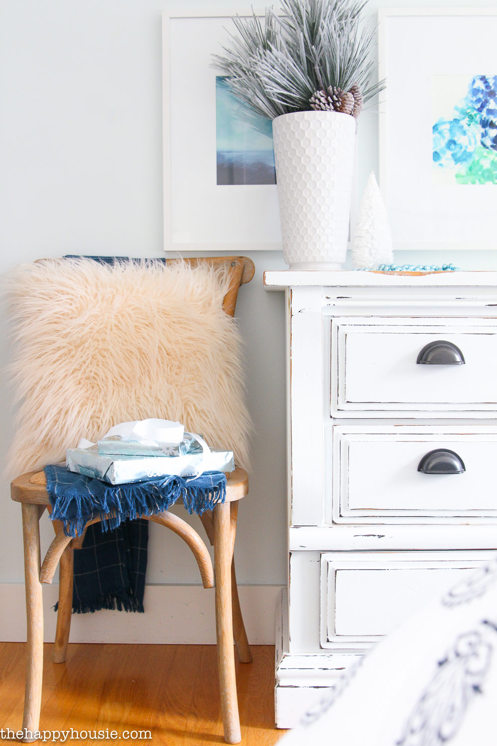 A small wooden chair has a fluffy faux fur pillow on it.