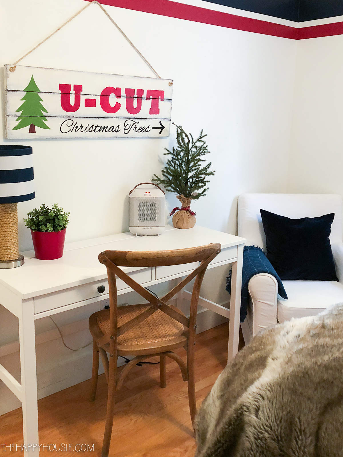 A small white desk in the guest bedroom with a Christmas tree on it.