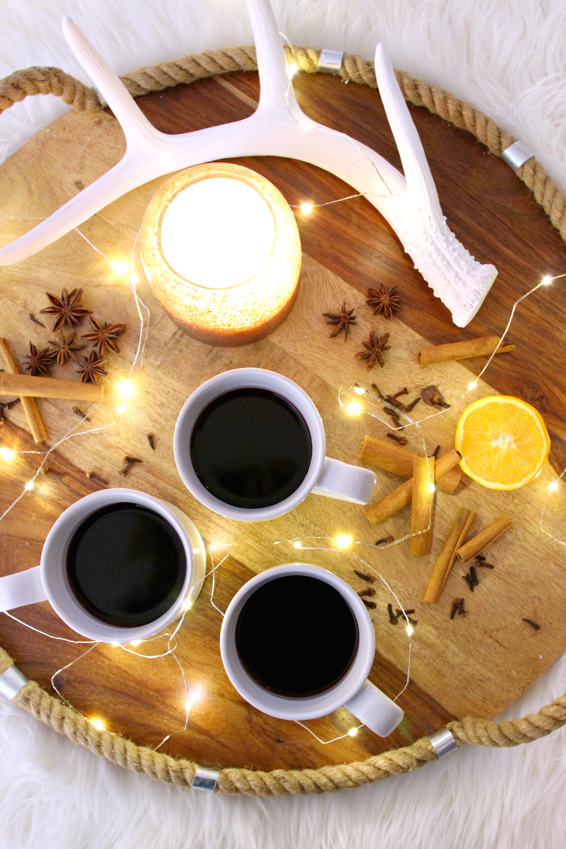 The mulled wine on a wooden tray with faux antlers, cut orange and cinnamon sticks.