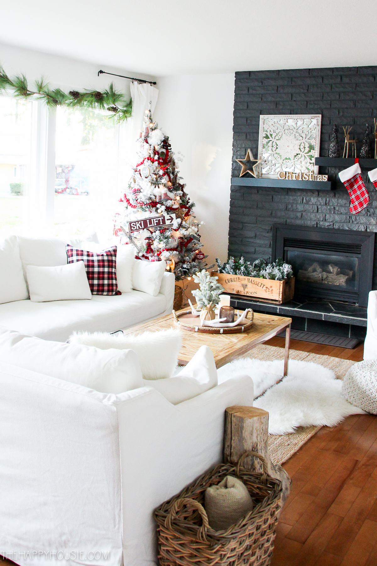 White neutral couches, a dark grey fireplace and stone and wood floors.