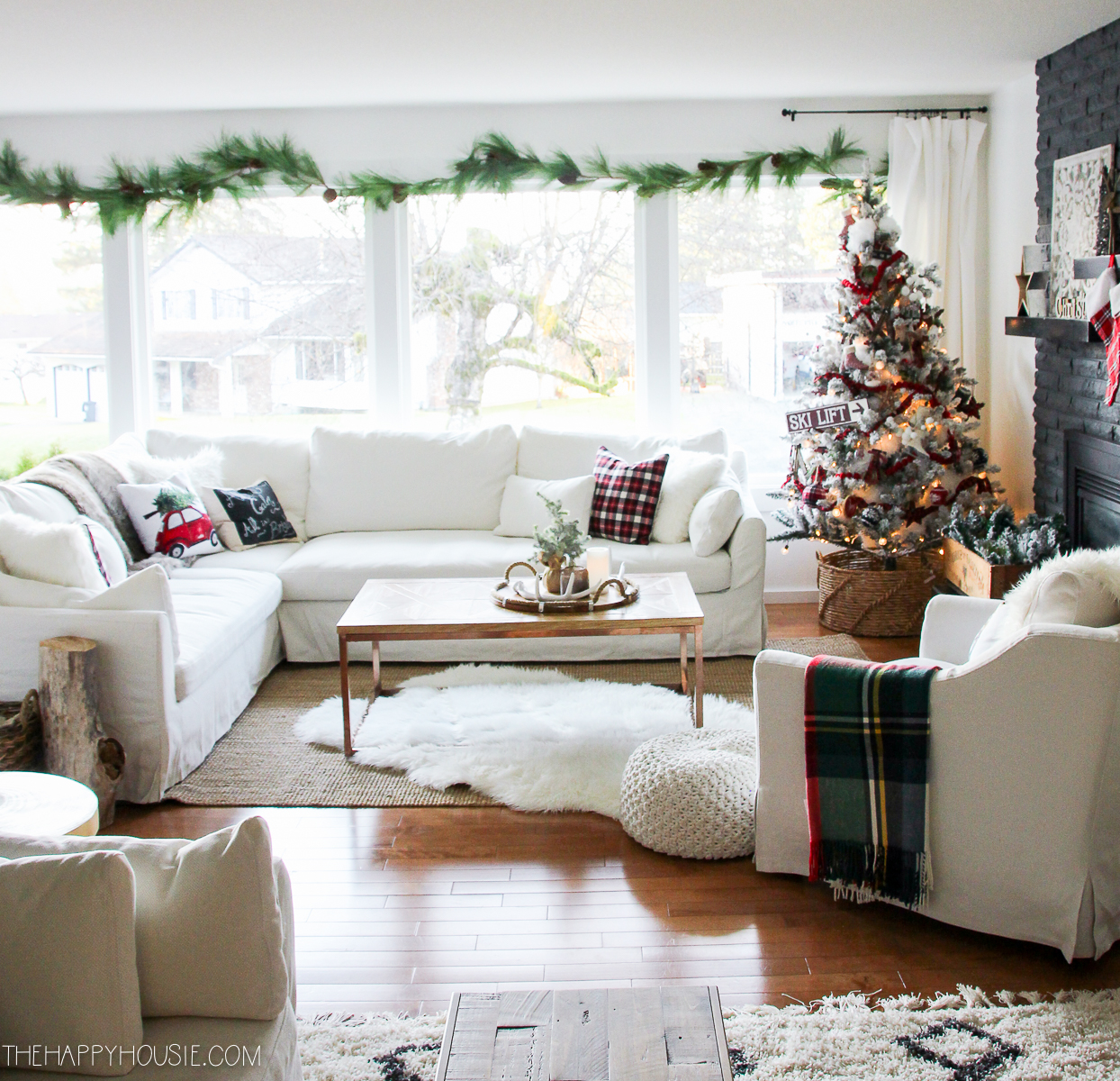 Light and bright living room with a tartan blanket and a tree in the corner of the room.