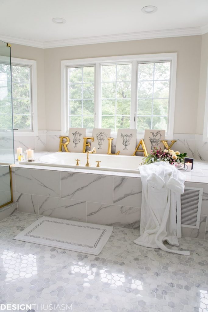 Marble bathtub with gold faucet and a gold sign that says relax.