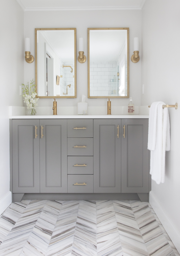 Gold and grey details in this bathroom with chevron patterned flooring.