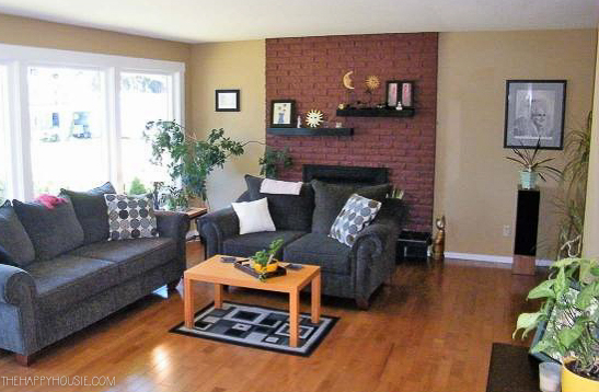 Living room with dark yellow walls and a red brick fireplace.