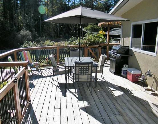 a large wooden back deck with a patio table and umbrella 