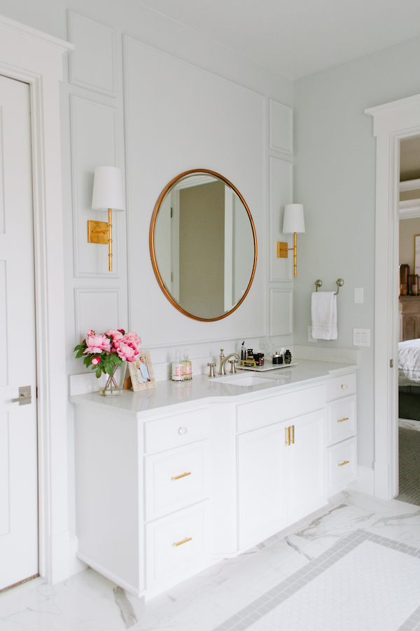 A rounded gold mirror above a white cabinet.