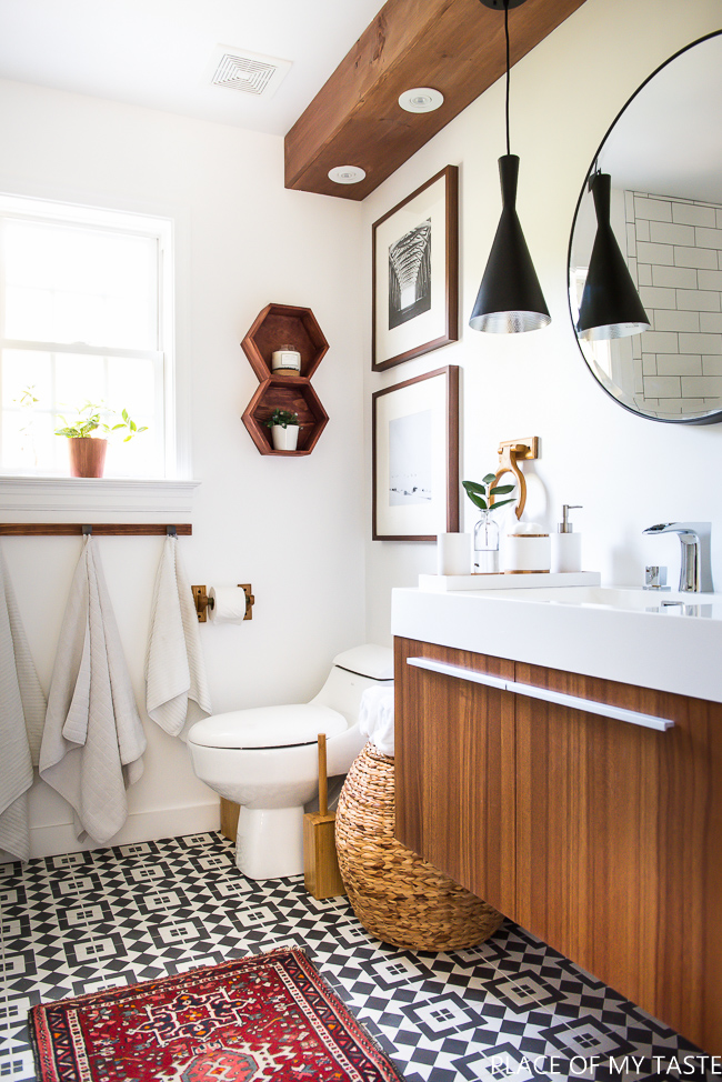 A white bathroom with dark brown wooden vanity cupboard and a wooden beam.