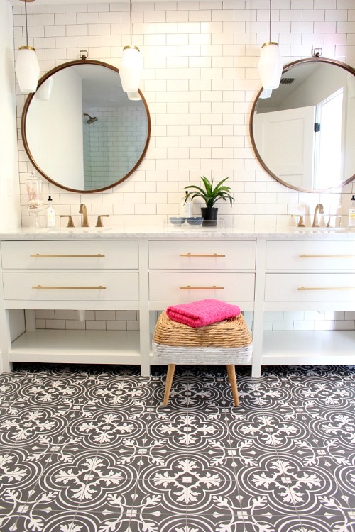A large white vanity with a small stool in front of it, and two large round mirrors.
