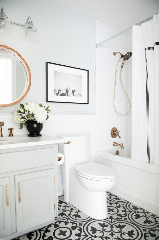 A white bathroom with a black and white picture on the wall behind the toilet.