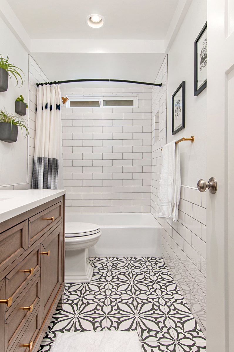 A white bathroom with a black and white floral patterned floor.