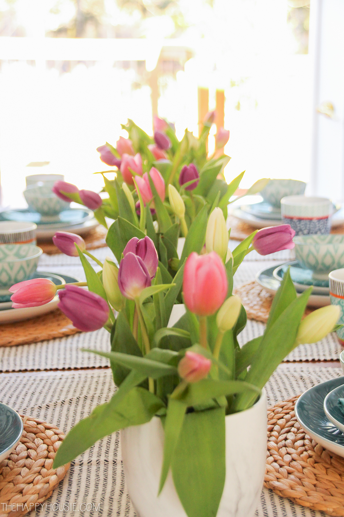 Pink tulips in a white vase on the table.