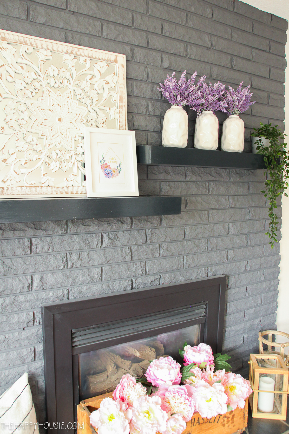 Decorative candles beside the peonies on the fireplace mantel.