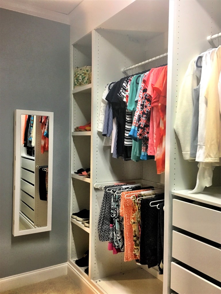 a walk-in closet that uses the Ikea PAX wardrobe system to give a built-in closet feel