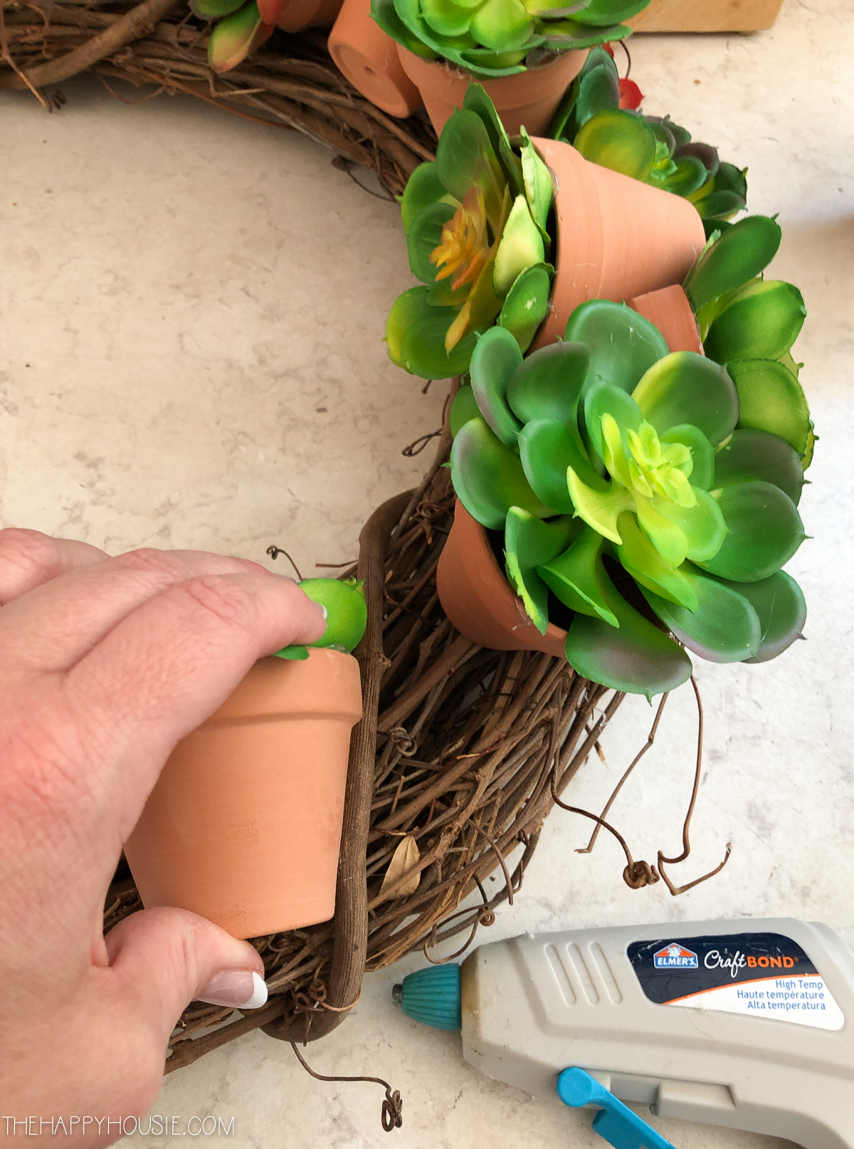 Attaching the succulent pots to the grapevine wreath.