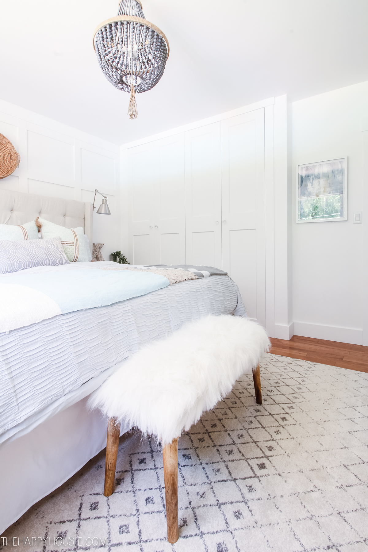 A white faux fur throw is on a bench in the bedroom.