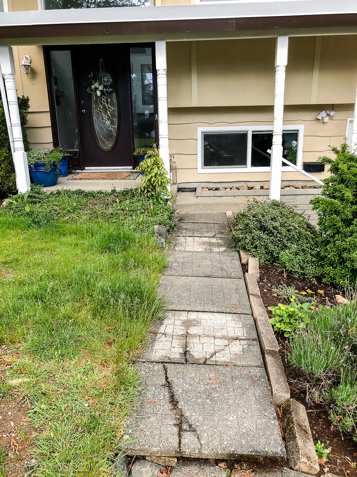 The path to the house with cracked and uneven slabs of concrete.