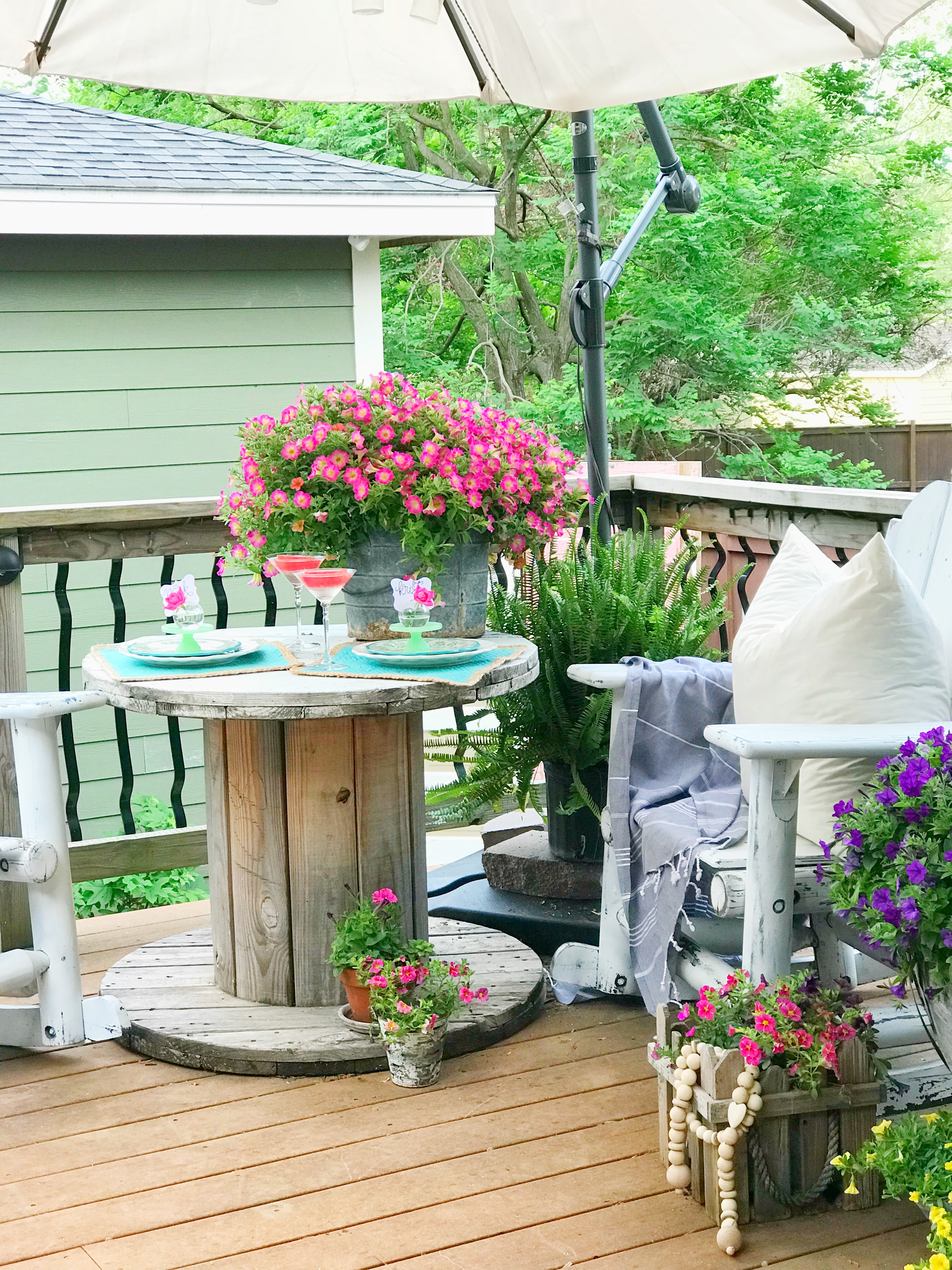 A back deck of a house filled with pots of flowers.