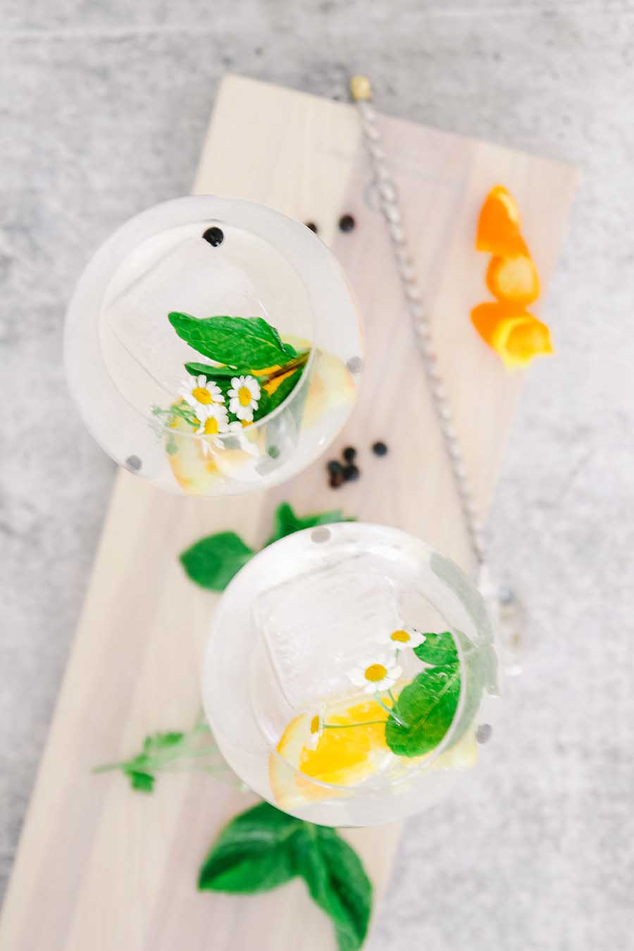 Gin and tonic in glasses with daisies in them.