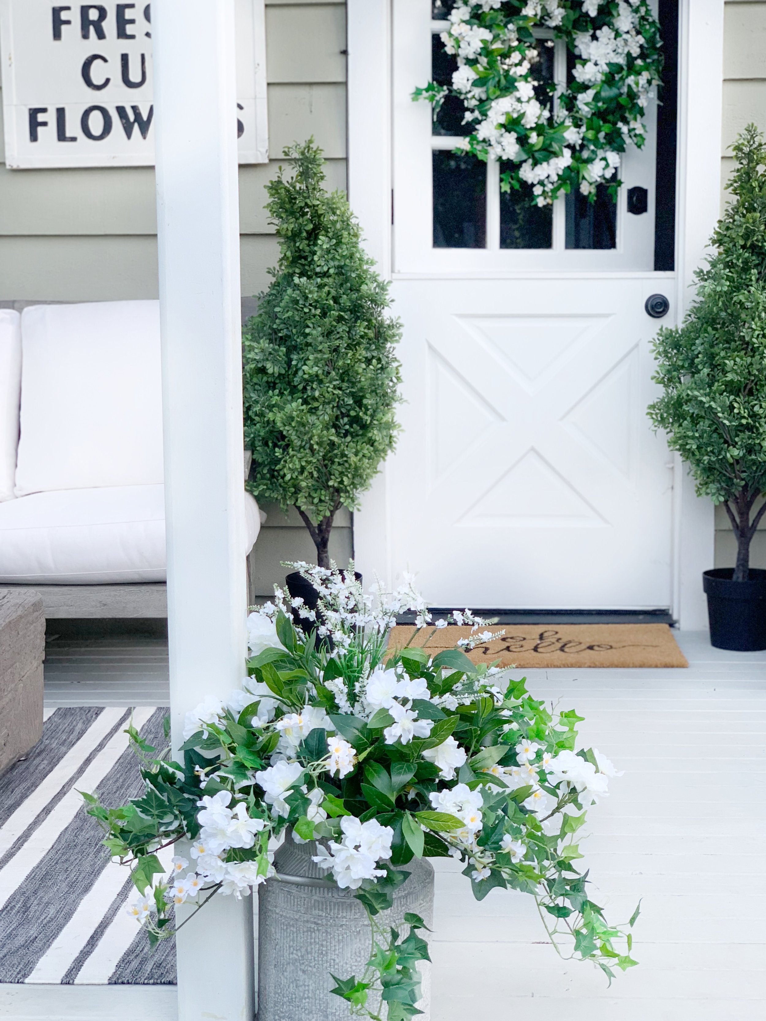White flowers and greenery on the front porch.
