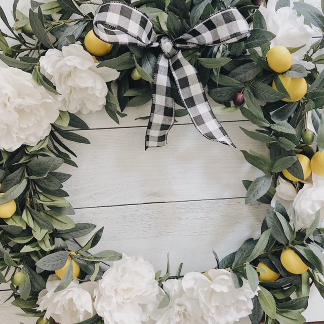 A white peony wreath with a black and white bow.