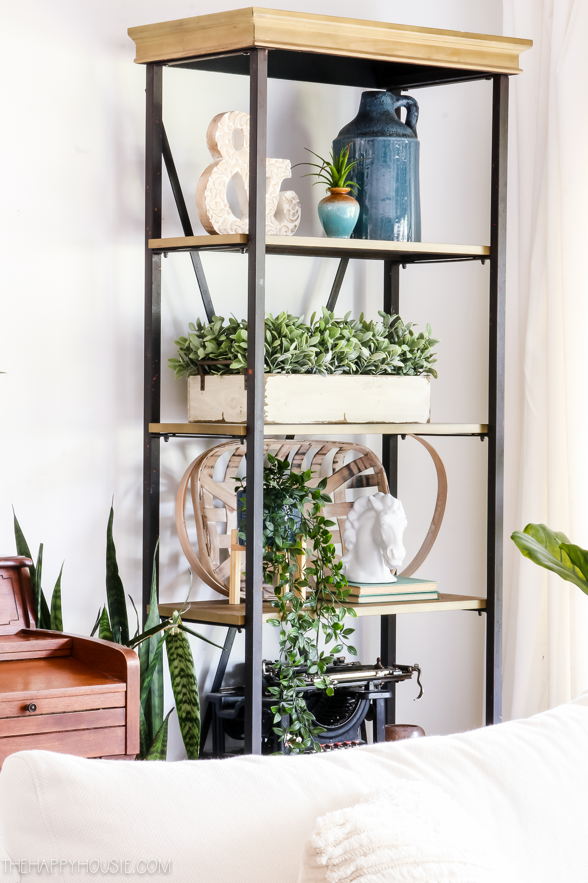 The open shelving unit has an antique typewriter, potted plants, and various knick knacks.