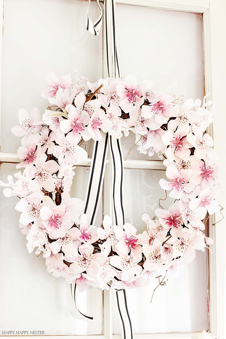 A white and pink floral wreath hanging with ribbon.