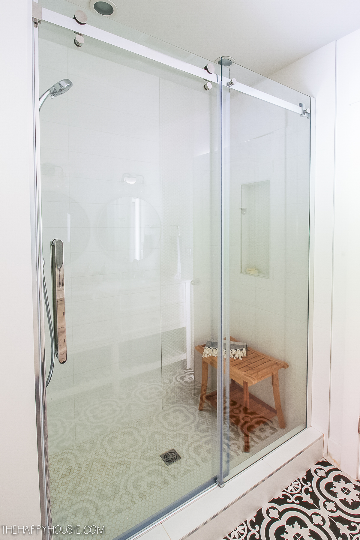A small wooden bench is inside the shower stall.