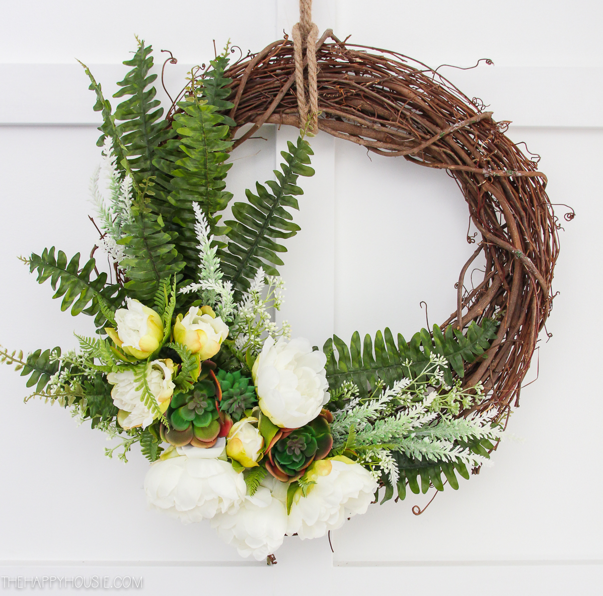 Grapevine wreath with fern, and white flowers.
