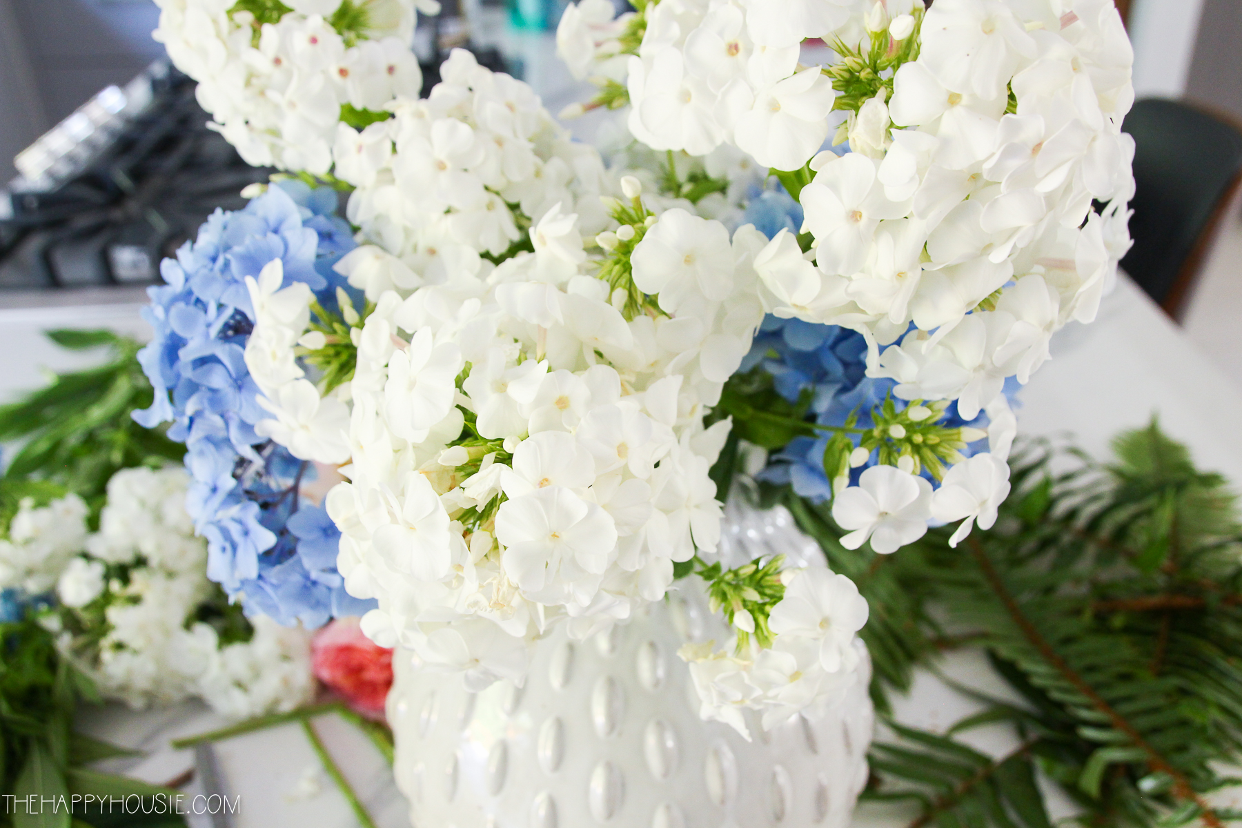 Layering white hydrangeas in between the blue ones in the white vase.