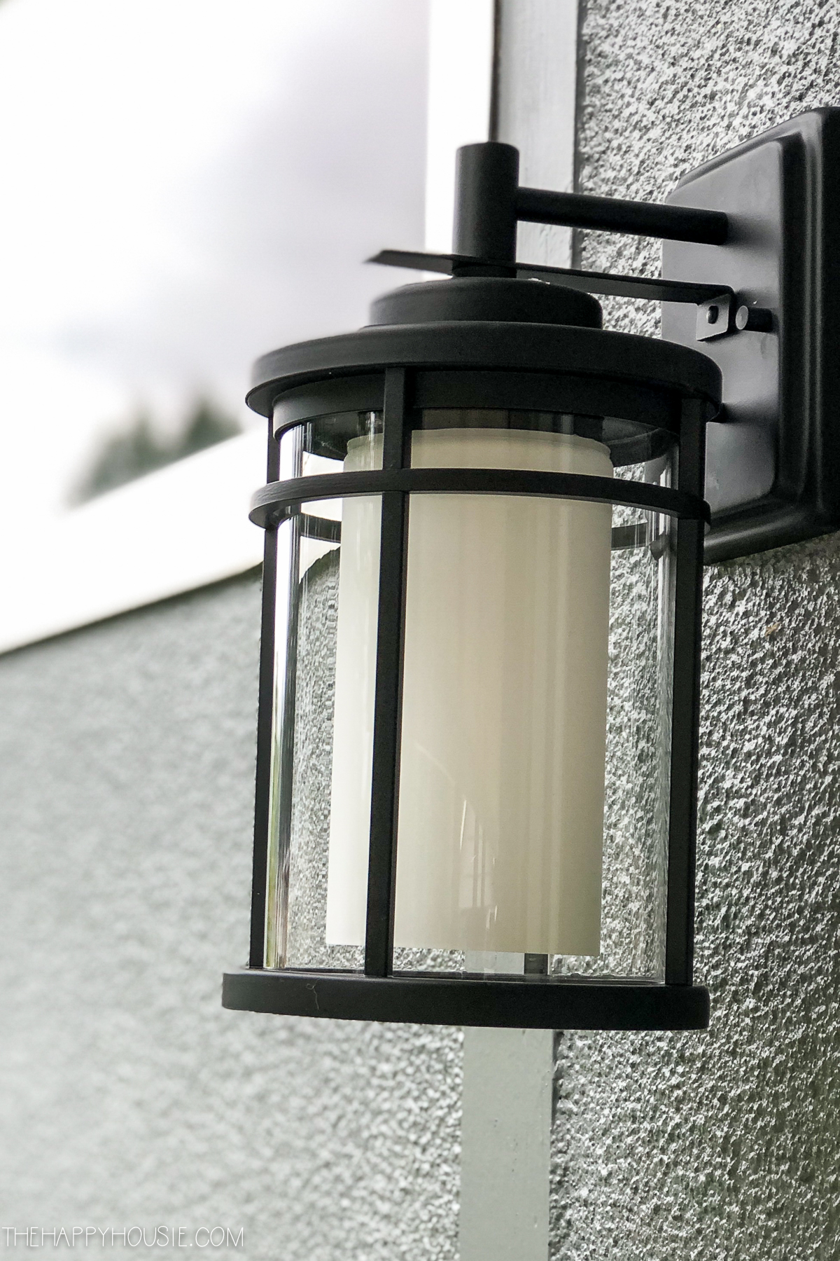 A black and white light hanging on the outside of the house.