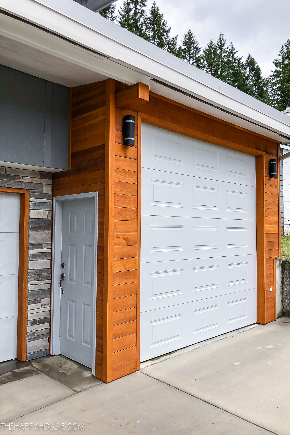 A white garage door with cedar siding.