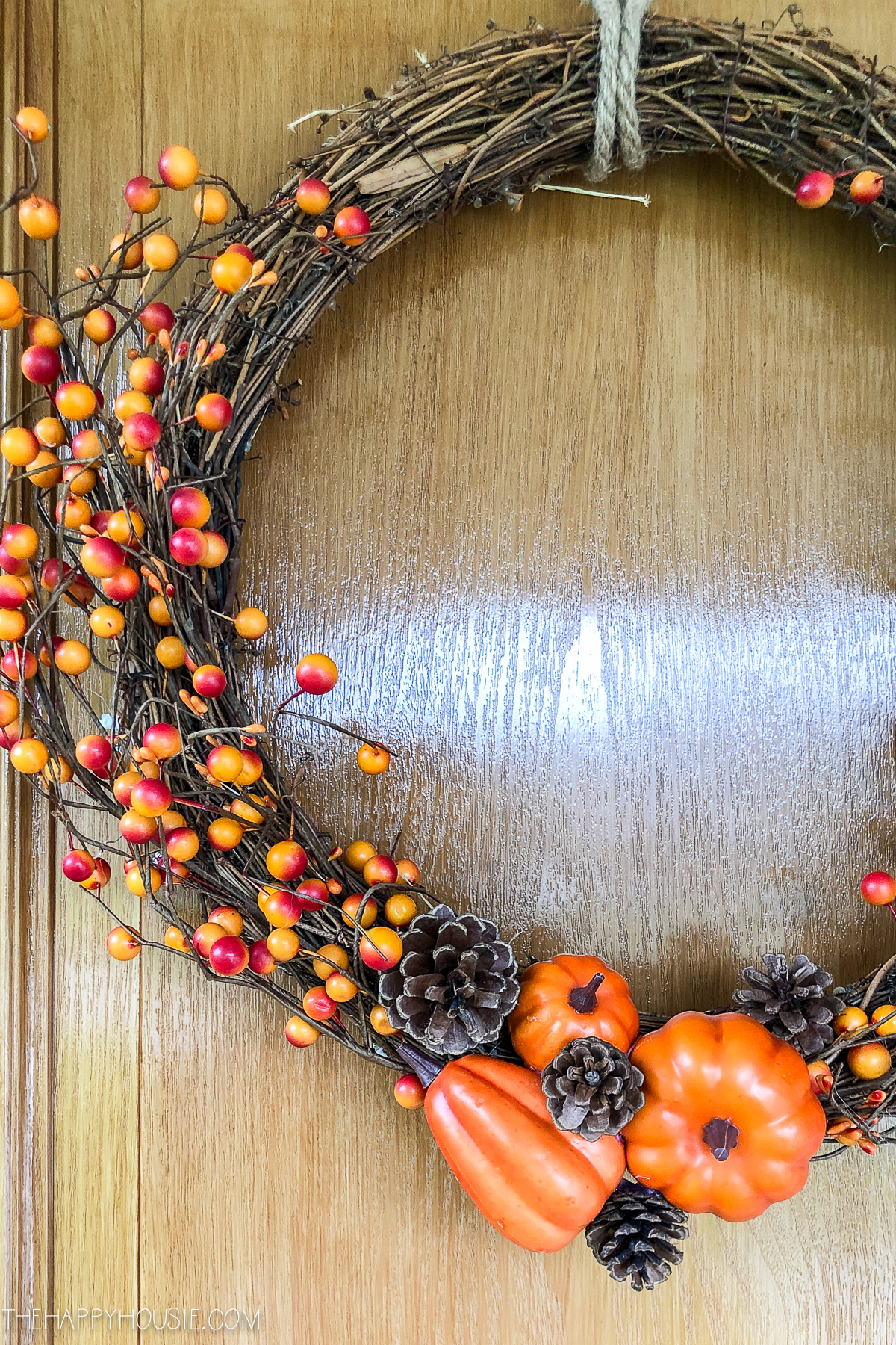 A fall wreath with mini pumpkins and pine cones.