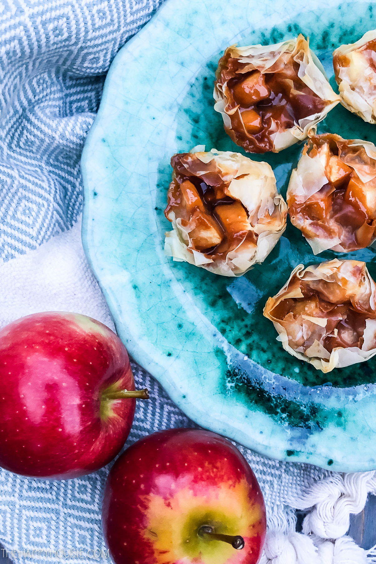The phyllo bites on a plate with two apples beside it.
