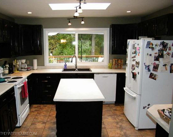 a dark brown kitchen with a small island and tile floors before being renovated