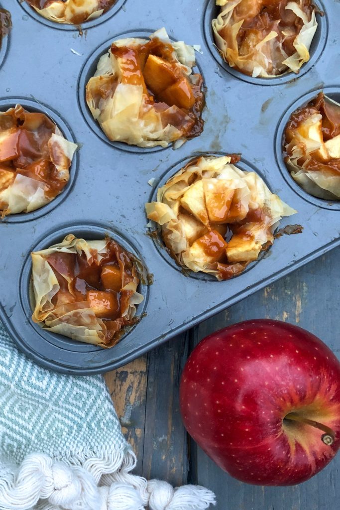 A muffin tin filled with phyllo and caramel and apple bites just baked.