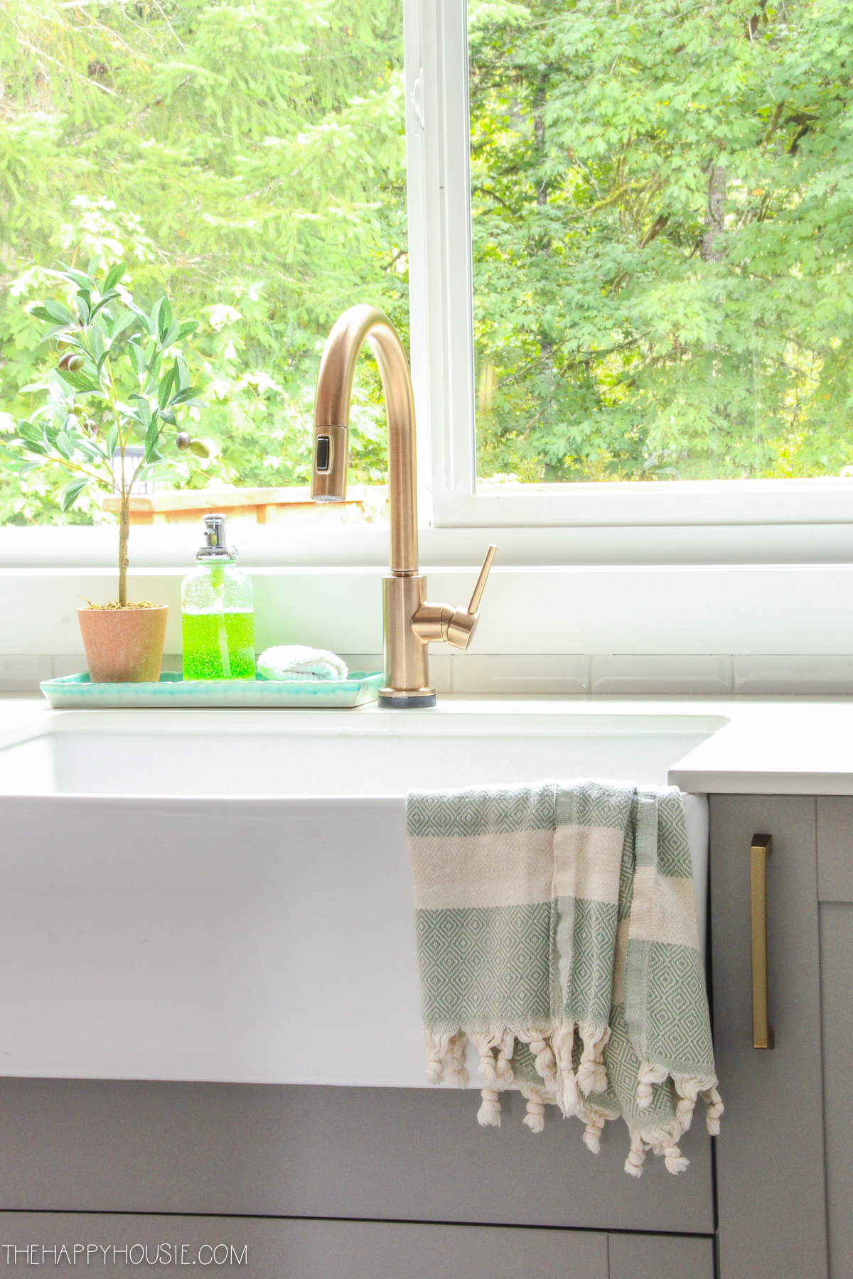 A brass faucet and a farmhouse sink are in the kitchen.