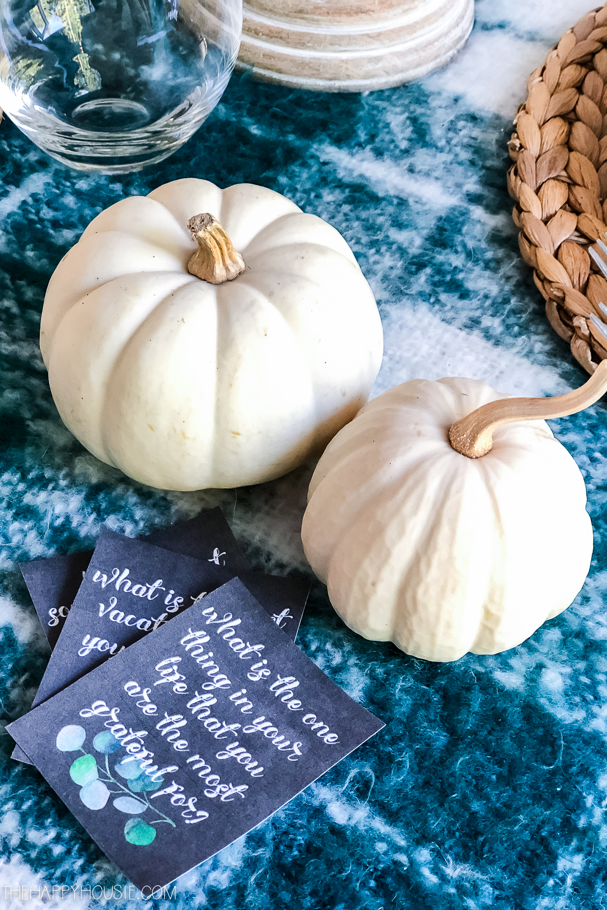There are white pumpkins on the blue tablecloth.