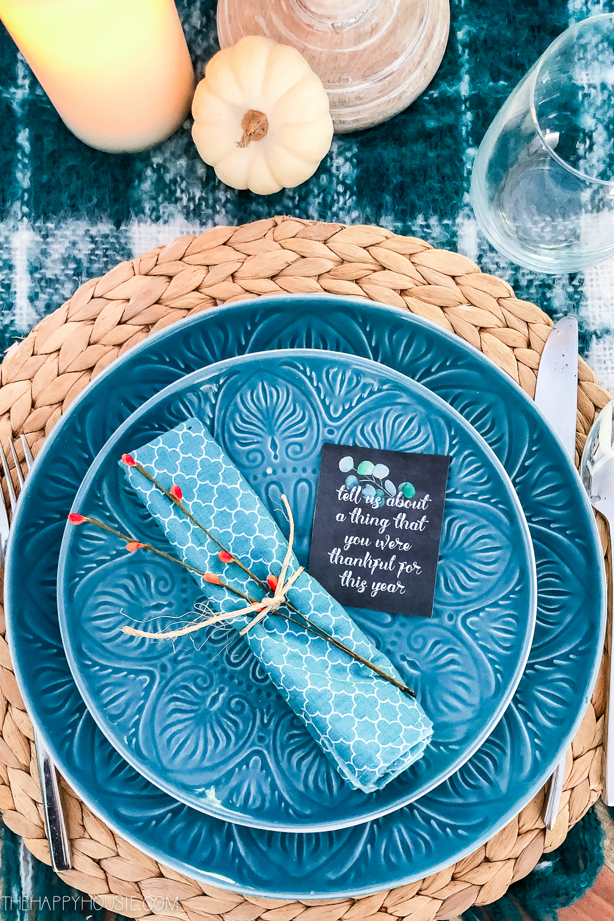 Blue plates and napkin with a sprig of branch tied around it.