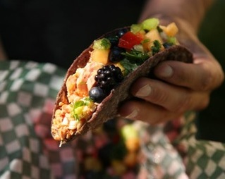 Holding a taco with fruit in it.