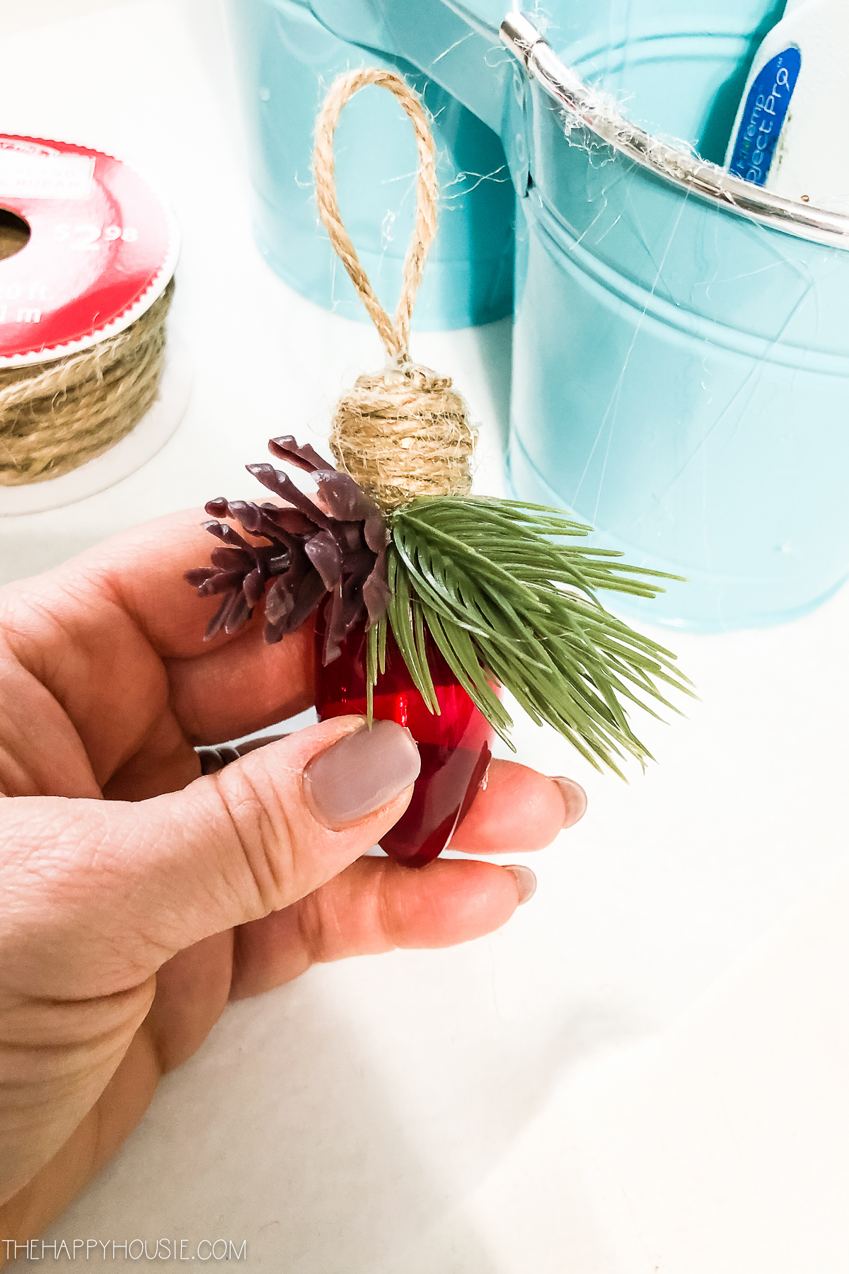 Using the hot glue gun to glue faux evergreen and pinecone.