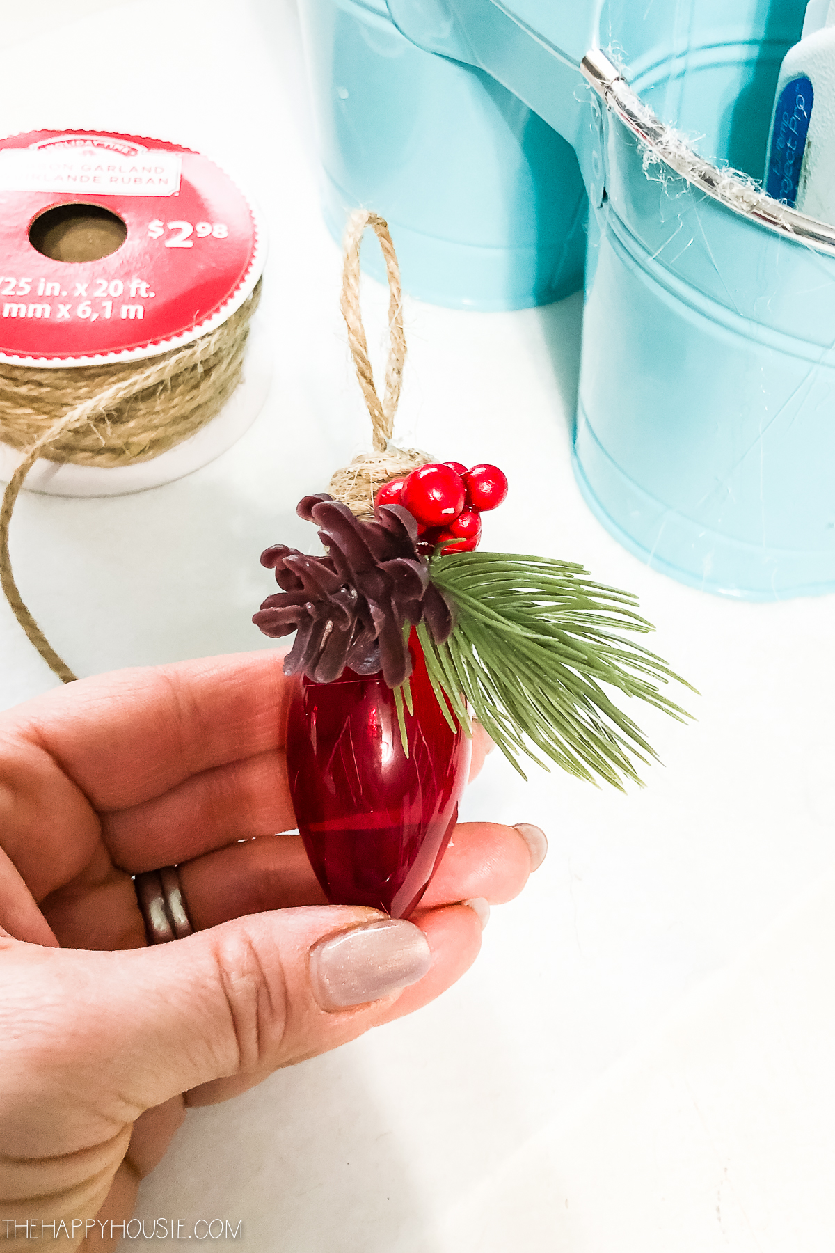 Holding the ornament in the hand with red berries on it.