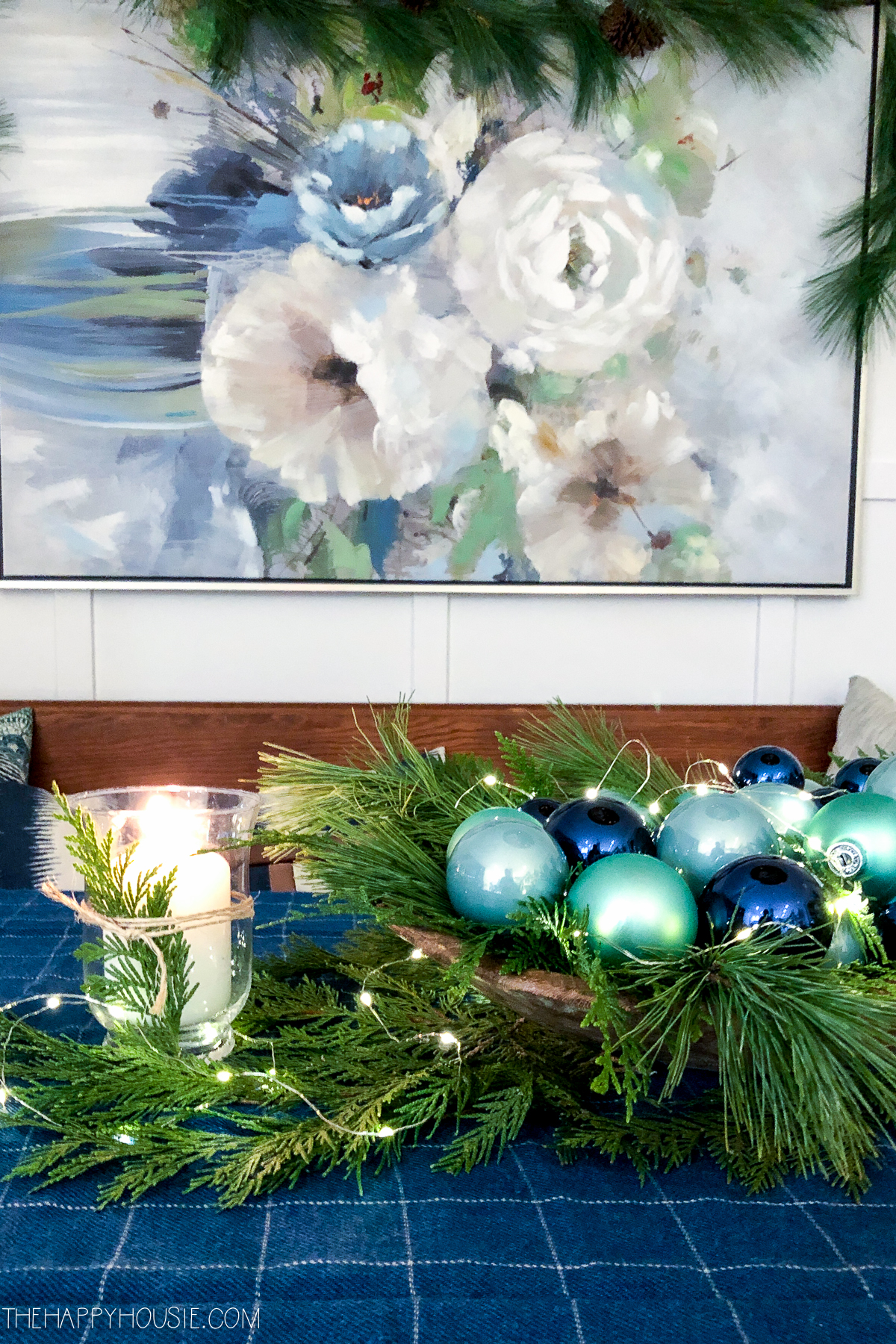 There is a large floral picture behind the table set for Christmas.