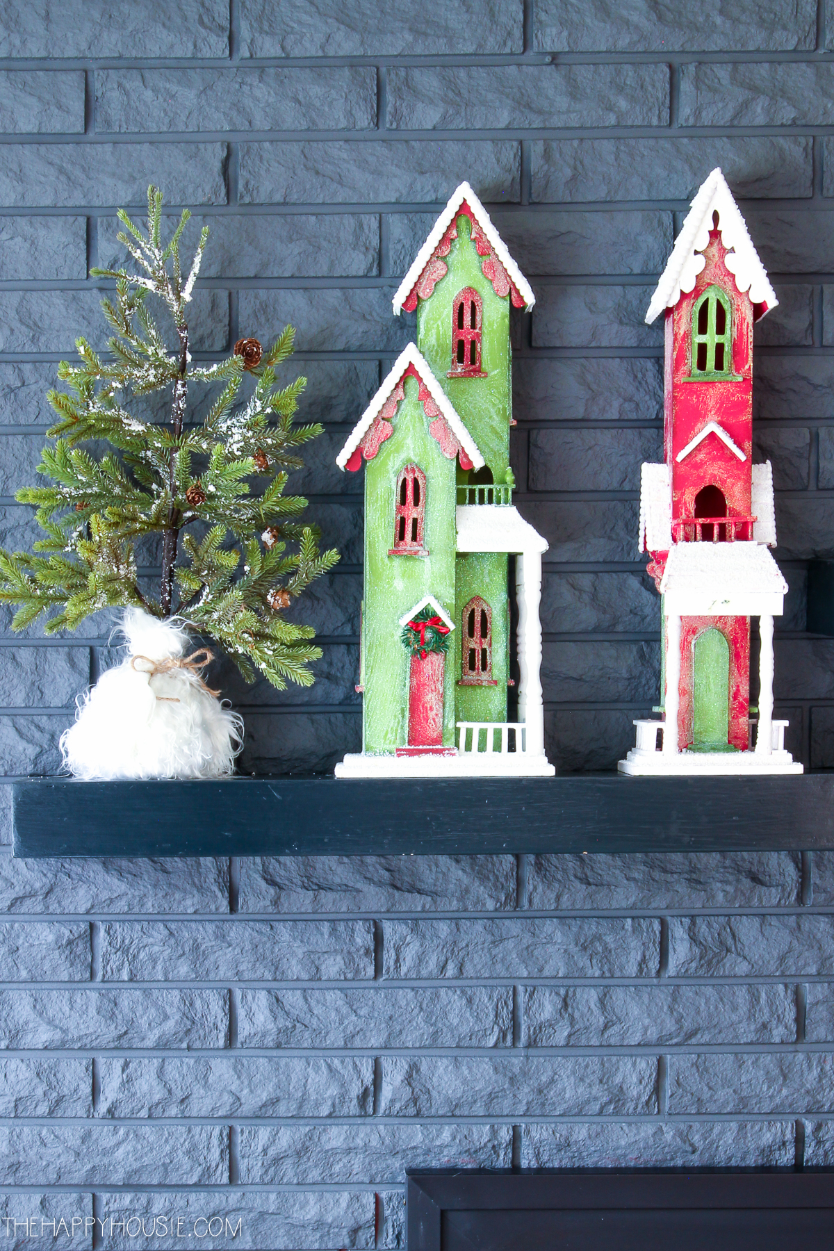 Up close of the village and mini Christmas tree on the shelf.