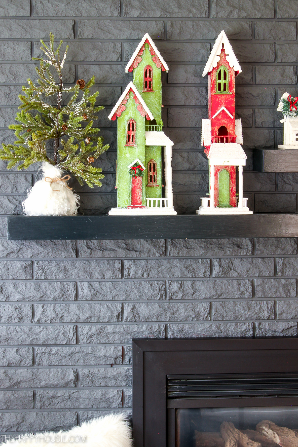 Little holiday village houses and a small Christmas tree is on the mantel.