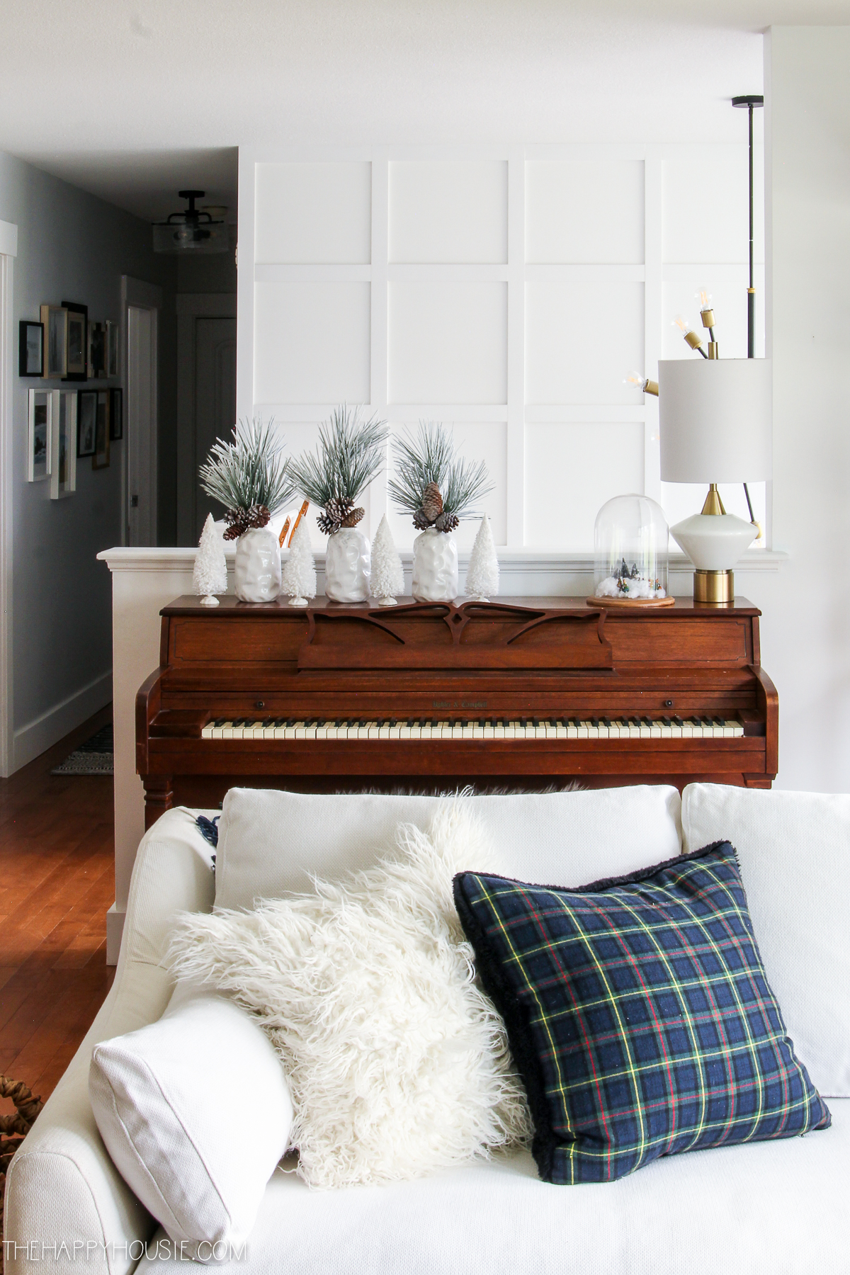 A wooden piano is behind the white couch in the living room.