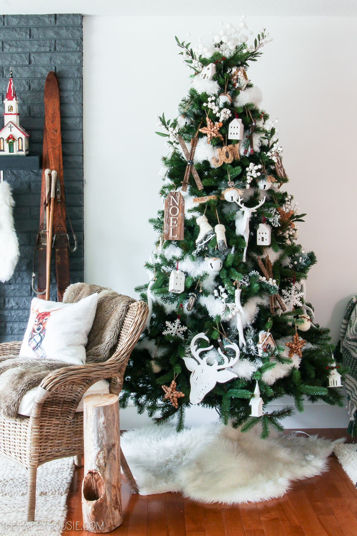 A small Christmas tree is in the corner of the room with a faux fur white skirt.