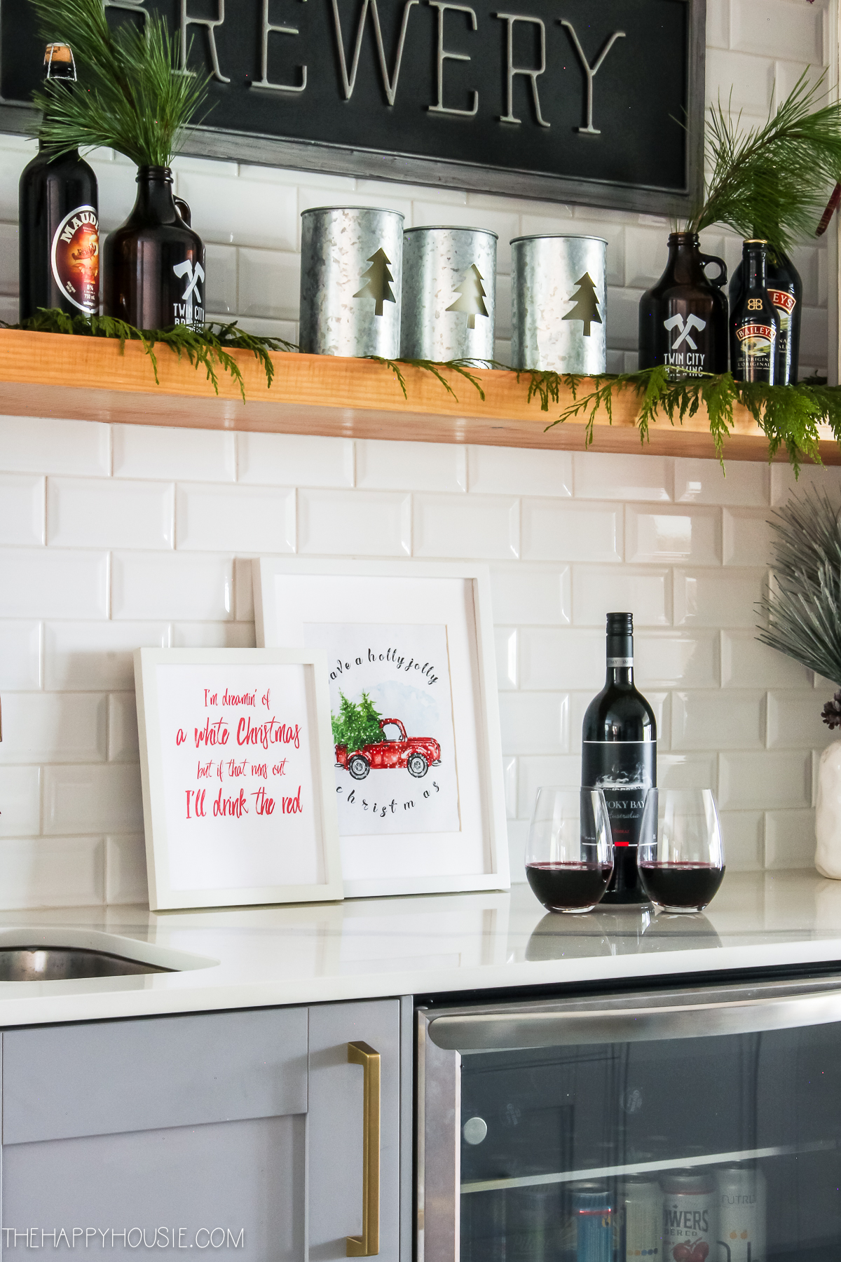 A bottle of red wine with two glasses is on the counter in the kitchen.